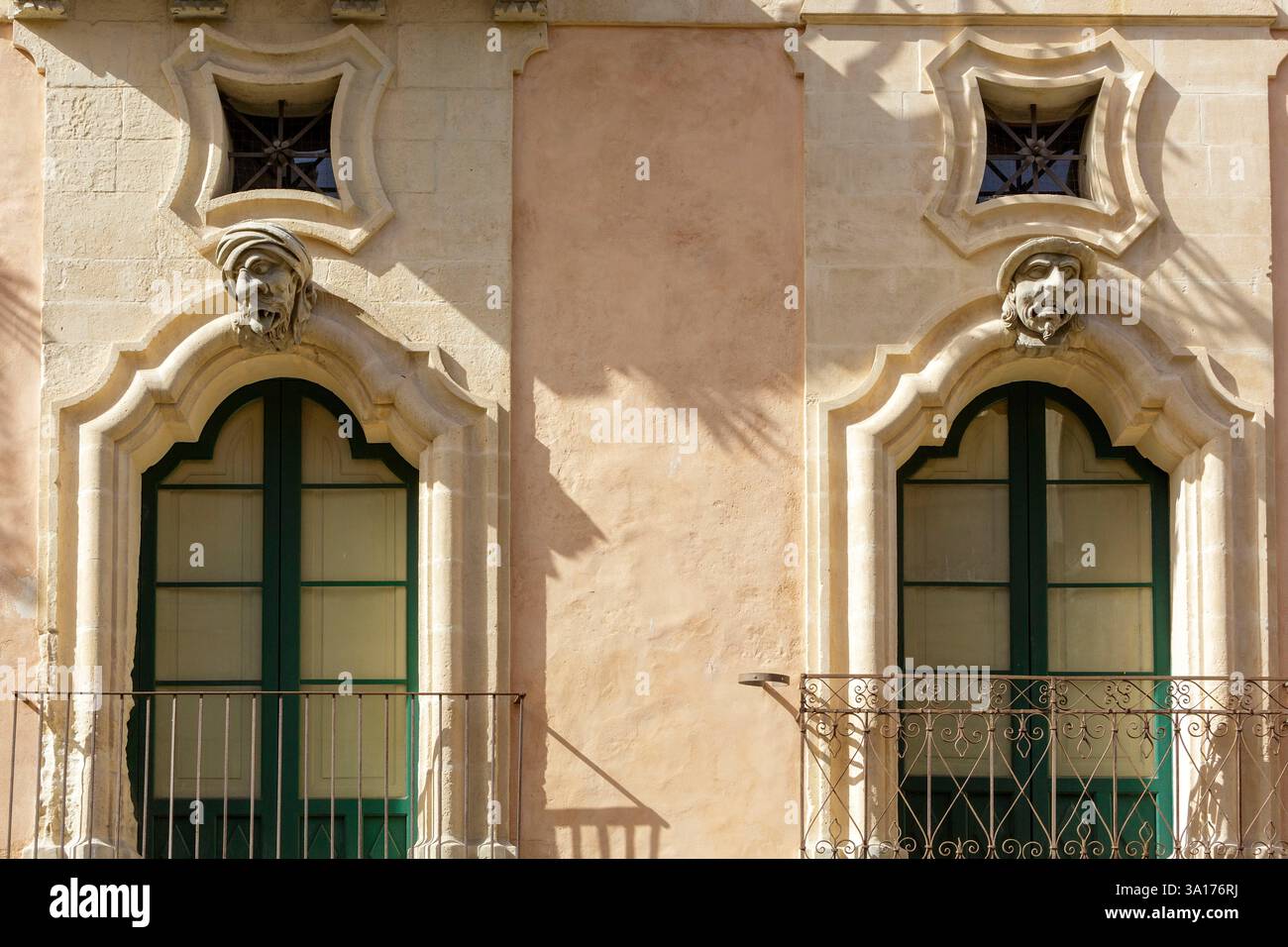Italia, Sicilia, Ragusa, città dichiarata Patrimonio dell'Umanità dall'UNESCO, facciata del Palazzo Bertini costruito in stile barocco nel XVIII secolo a Ragusa superiore (alta Ragusa) situato in corso Italia, due dei tre volti ridicoli sulla facciata tipica dello stile barocco che rappresenta il mendicante a sinistra e il nobile a destra Foto Stock