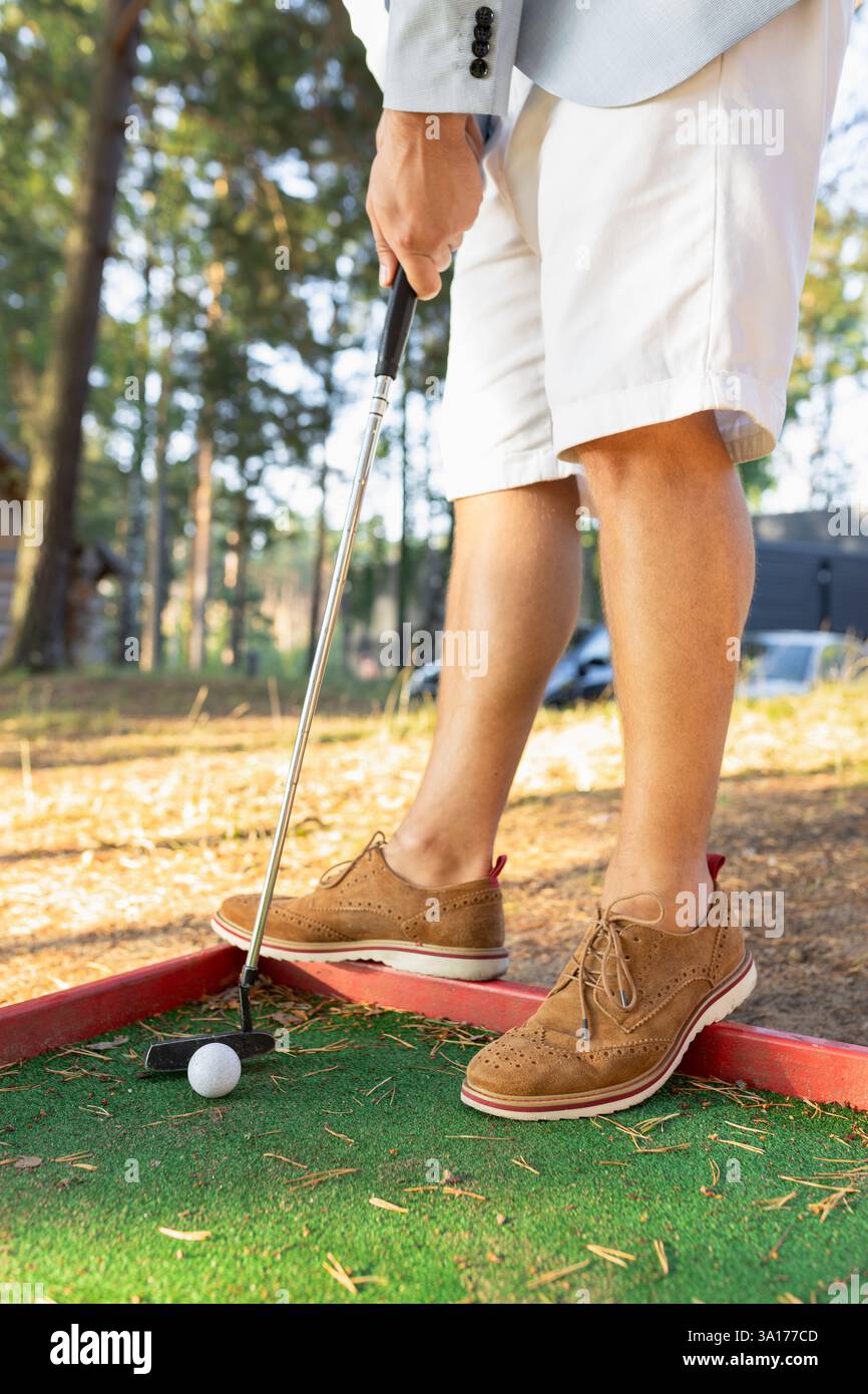 Uomo elegante in pantaloncini bianchi e scarpe scamosciate con mini golf club Foto Stock