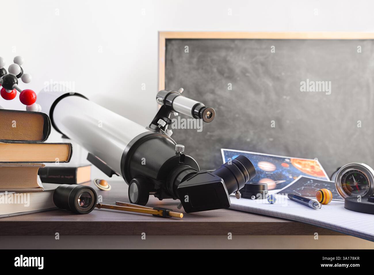 Tavolo per studenti di astronomia con materiali e strumenti dello studio e lavagna sullo sfondo. Vista frontale. Foto Stock