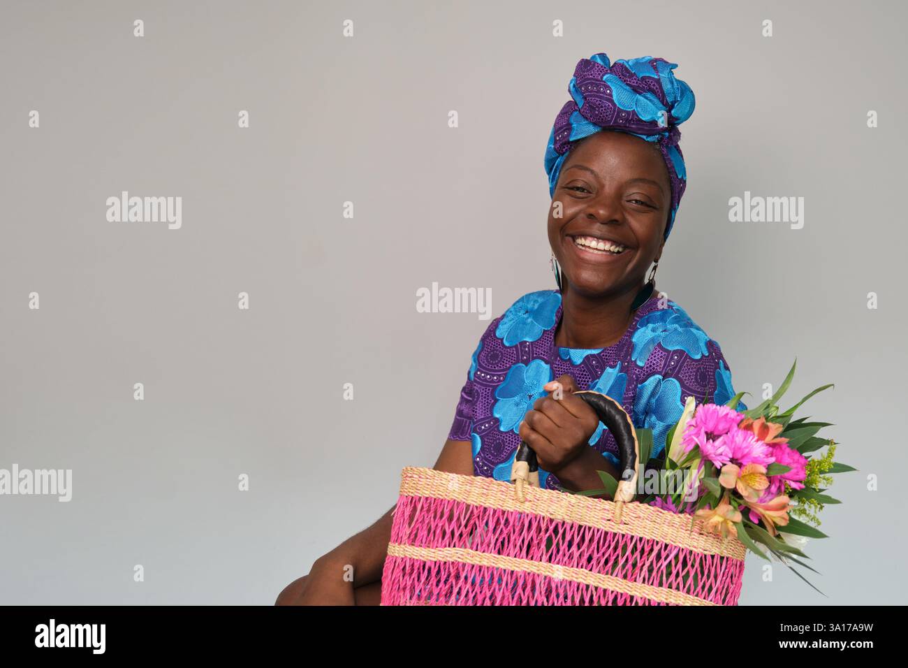 Donna sorridente con borsa in tessuto rosa e fiori colorati Foto Stock