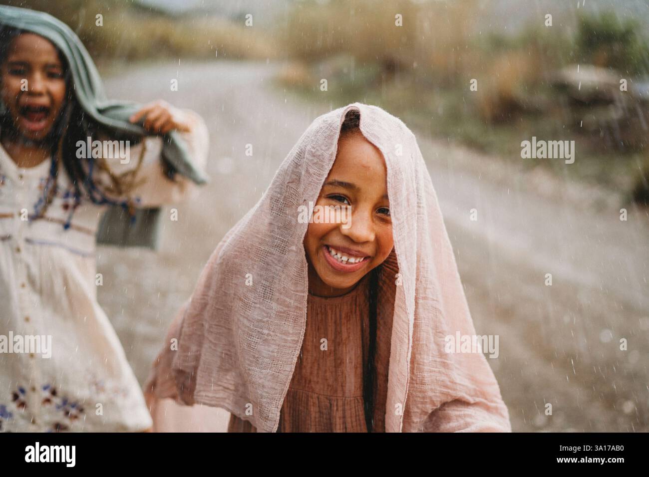 Ragazze nere che sorridono ballando sotto la pioggia in campagna Foto Stock