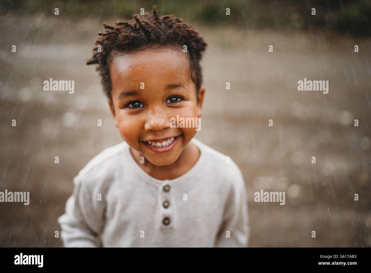 Ragazzo nero sorridente ballando sotto la pioggia in campagna Foto Stock