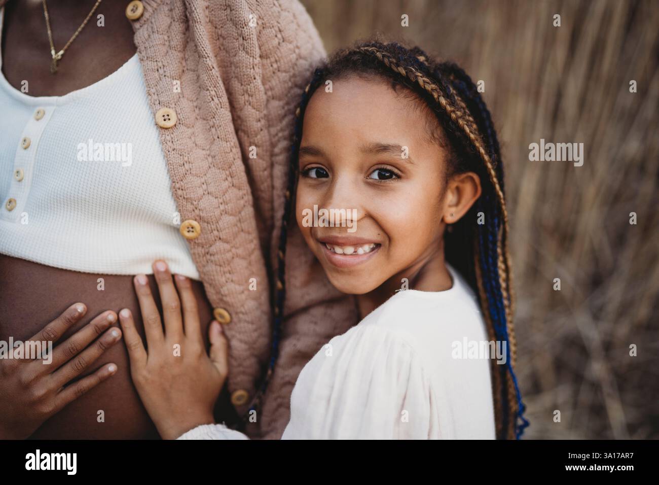 Madre incinta nera e figlie di razza mista che toccano la pancia Foto Stock