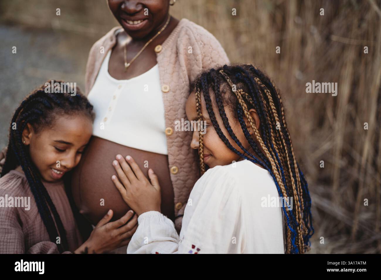 Madre incinta nera e figlie di razza mista che toccano la pancia Foto Stock