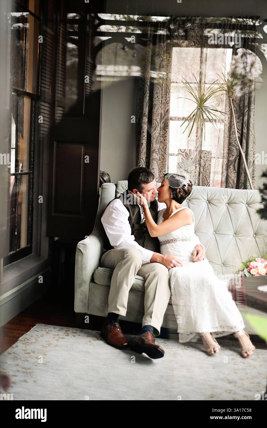 La sposa e lo sposo condividono un bacio romantico mentre si siede su un vintage Foto Stock