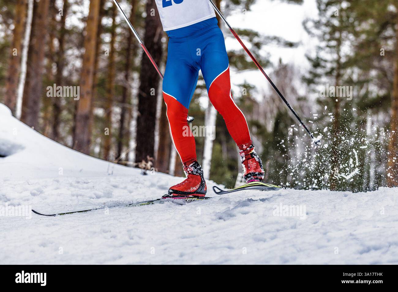 sciatore delle gambe e bastoncini da sci, spruzzi di neve alle spalle Foto Stock