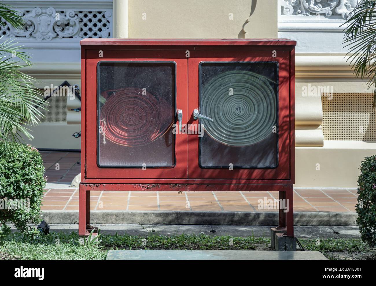 Un armadietto rosso per le apparecchiature antincendio o un armadietto antincendio (armadietto per tubi antincendio) del set antincendio si trova nel parco accanto all'edificio. Foto Stock
