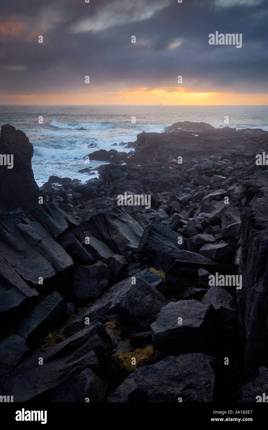 Spiaggia rocciosa di Valahnúkamöl al tramonto con onde coraggiose (Reykjanes - Islanda) Foto Stock