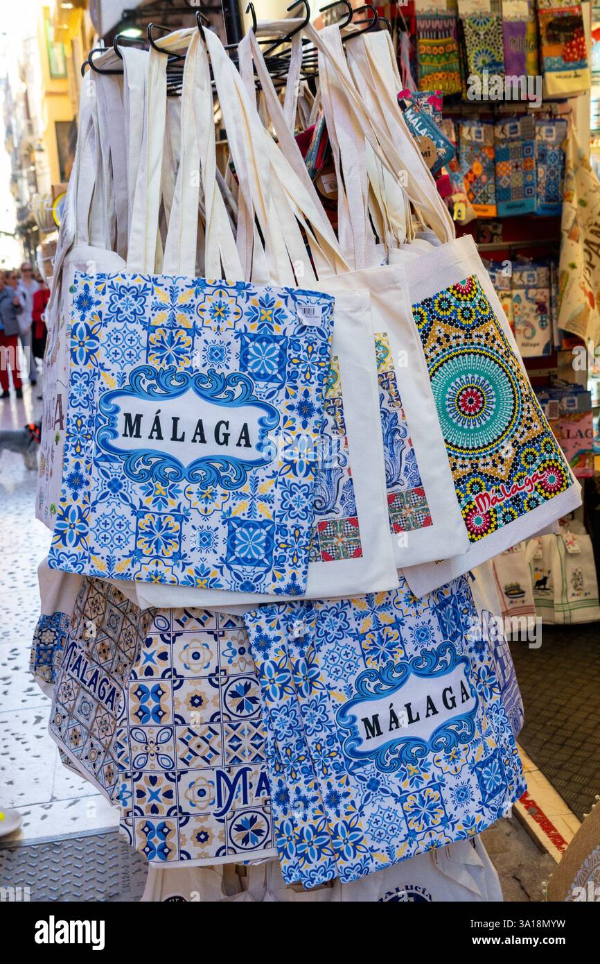 Esposizione di borse ricordo con un design Málaga in un negozio; ideale per viaggi, turismo e shopping. Le borse sono di colore blu e bianco. Foto Stock