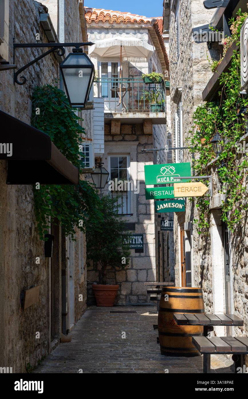 Budva, Montenegro - 23 agosto 2024: Vicolo stretto nella città vecchia con pub Foto Stock