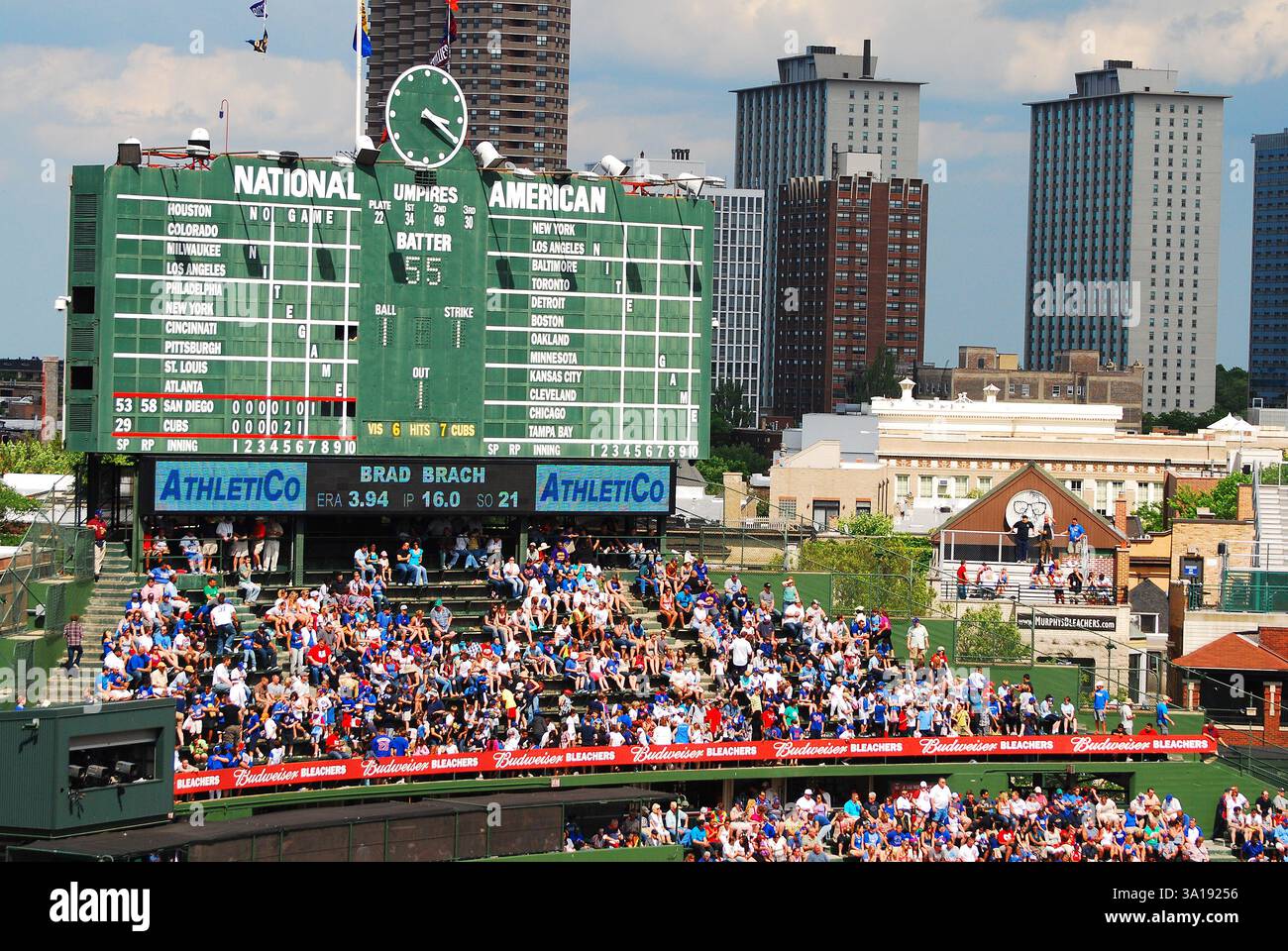 I tifosi si radunano per la squadra di baseball dei Chicago Cubs mentre sono seduti sotto lo storico tabellone a comando manuale a Wrigley Field Foto Stock