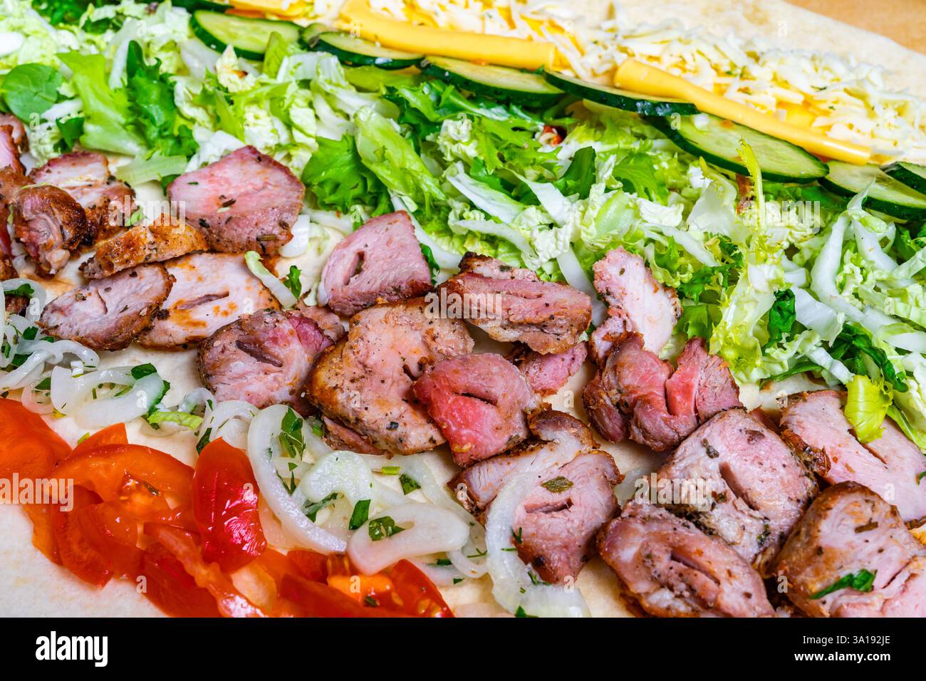 Un vivace taco propone carne alla griglia, strati di verdure fresche e formaggio fuso. Gli ingredienti colorati si uniscono in una tortilla, creando un Foto Stock