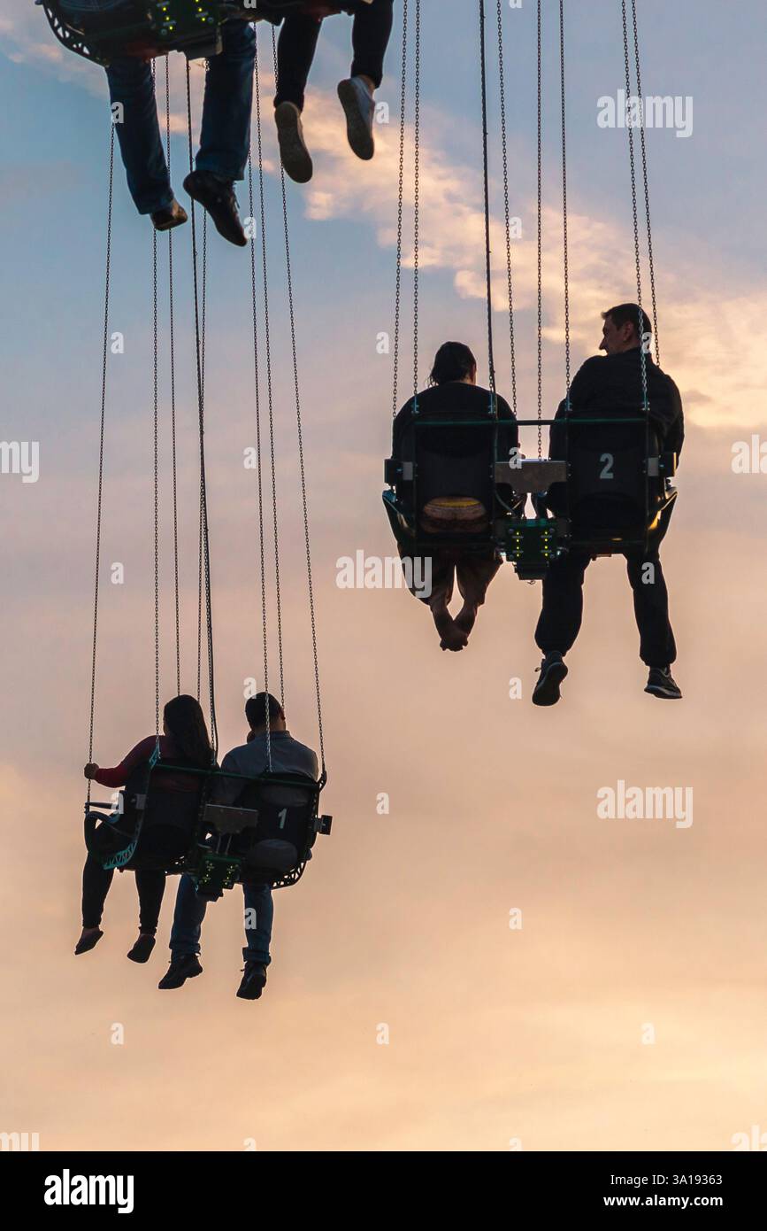 Persone in alto, vista delle coppie sospese durante un giro in fiera nel Prater Park, Vienna, Austria Foto Stock