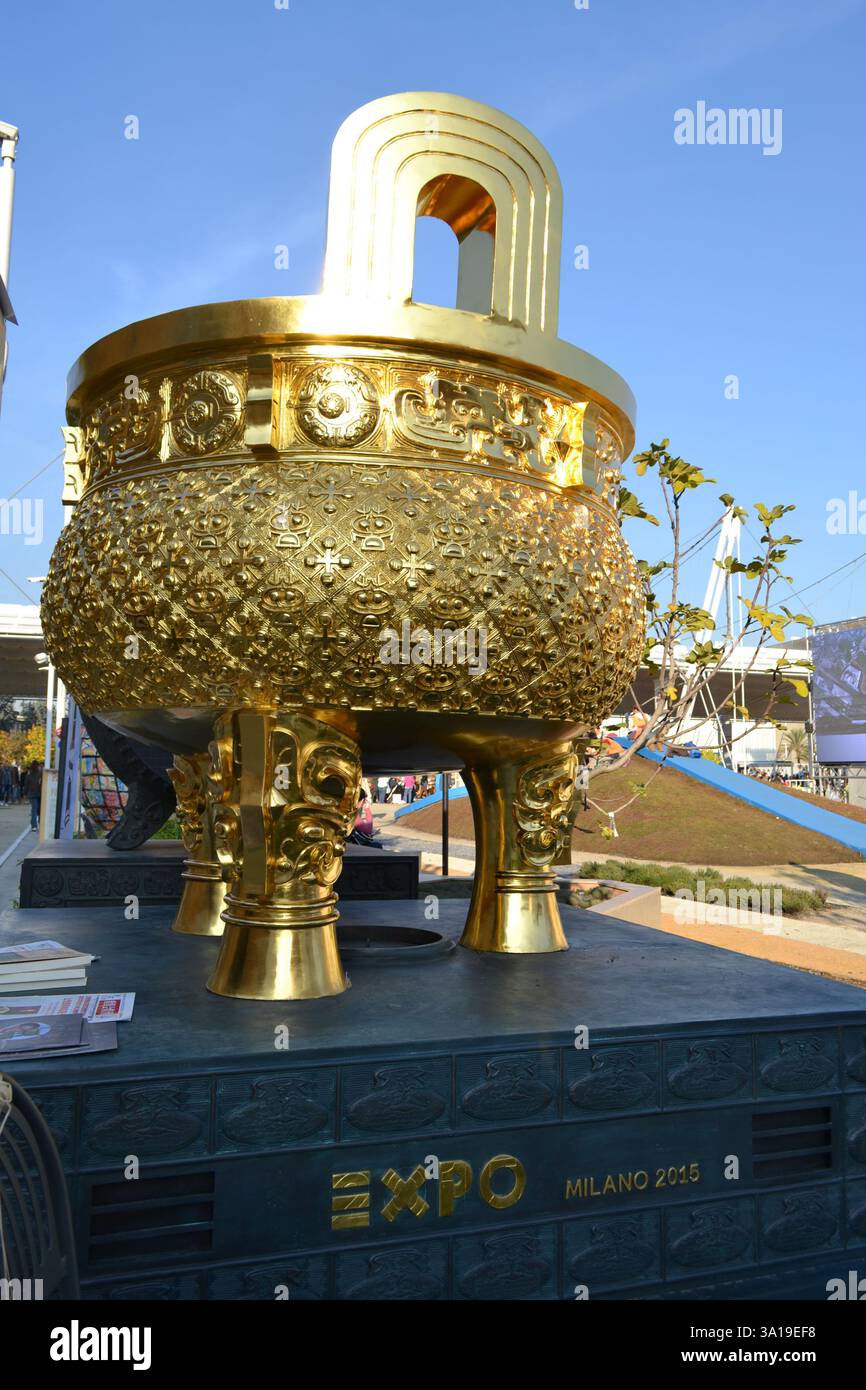 Padiglione China EXPO Milano 2015. Tradizionale bruciatore a incenso gigante cinese a tre zampe con treppiede dorato o ciotola del tesoro esposta all'aperto su piedistallo. Foto Stock