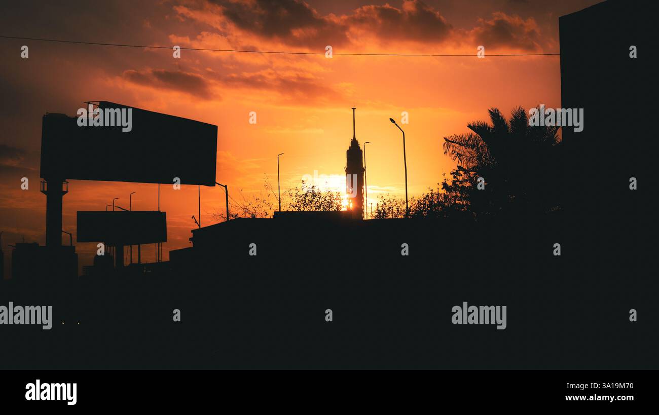 Mentre il sole bacia l'orizzonte, il cielo si mette a fuoco, sussurrando addio in tonalità d'oro, rosa e viola. Foto Stock