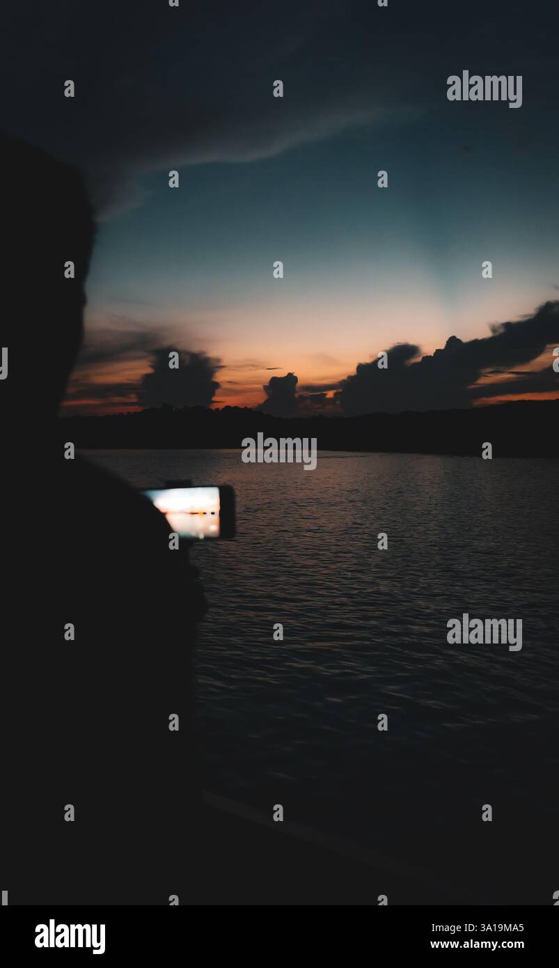 Mentre il sole bacia l'orizzonte, il cielo si mette a fuoco, sussurrando addio in tonalità d'oro, rosa e viola. Foto Stock