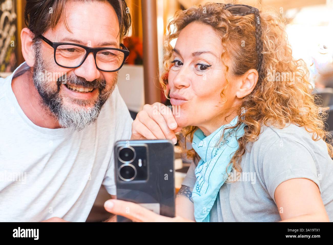 Coppia felice sorridente gusta il pranzo al ristorante e scatta foto con il cibo sul tavolo. Goditi il video durante il pranzo. Uomini e donne turisti che mangiano e bevono all'aperto e usano cellulari Foto Stock