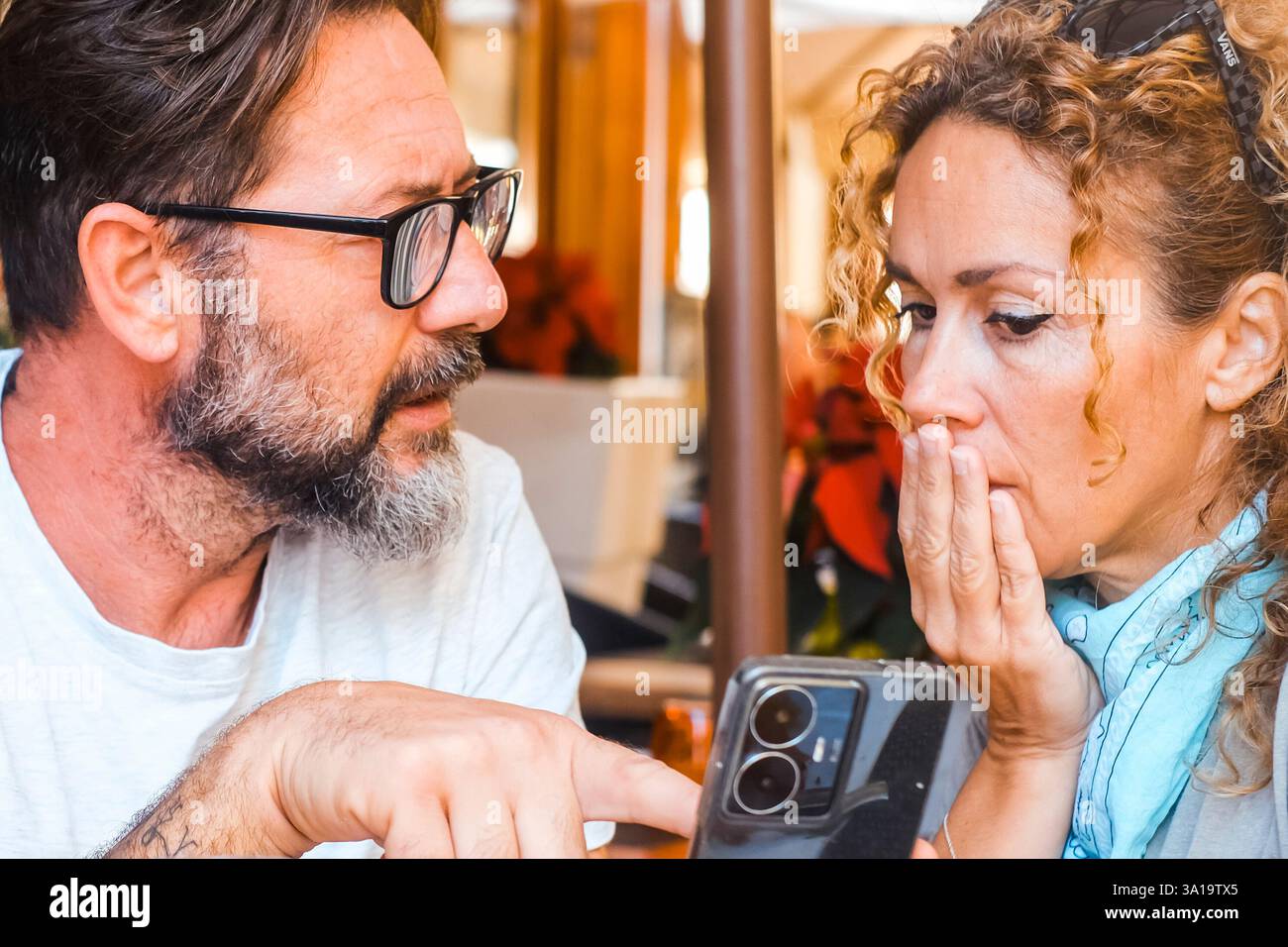 Un uomo arrabbiato che chiede spiegazioni a una donna che mostra contenuti imbrogliati sul suo cellulare. Concetto di infedeltà e gelosia. Problemi con chat sospette sul cellulare. uomo geloso che parla con una donna Foto Stock