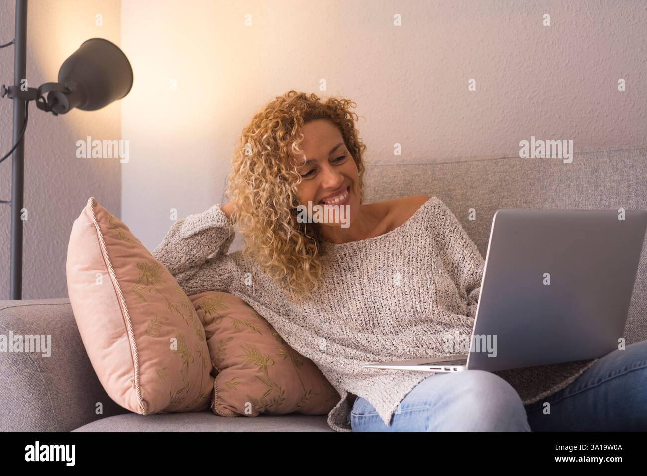 Una giovane donna adulta che usa il laptop a casa seduto sul divano scrivendo un messaggio. Moderna tecnologia online persone donne che praticano attività ricreative al chiuso da sole. Ricerca sul Web. Comunicazione Foto Stock