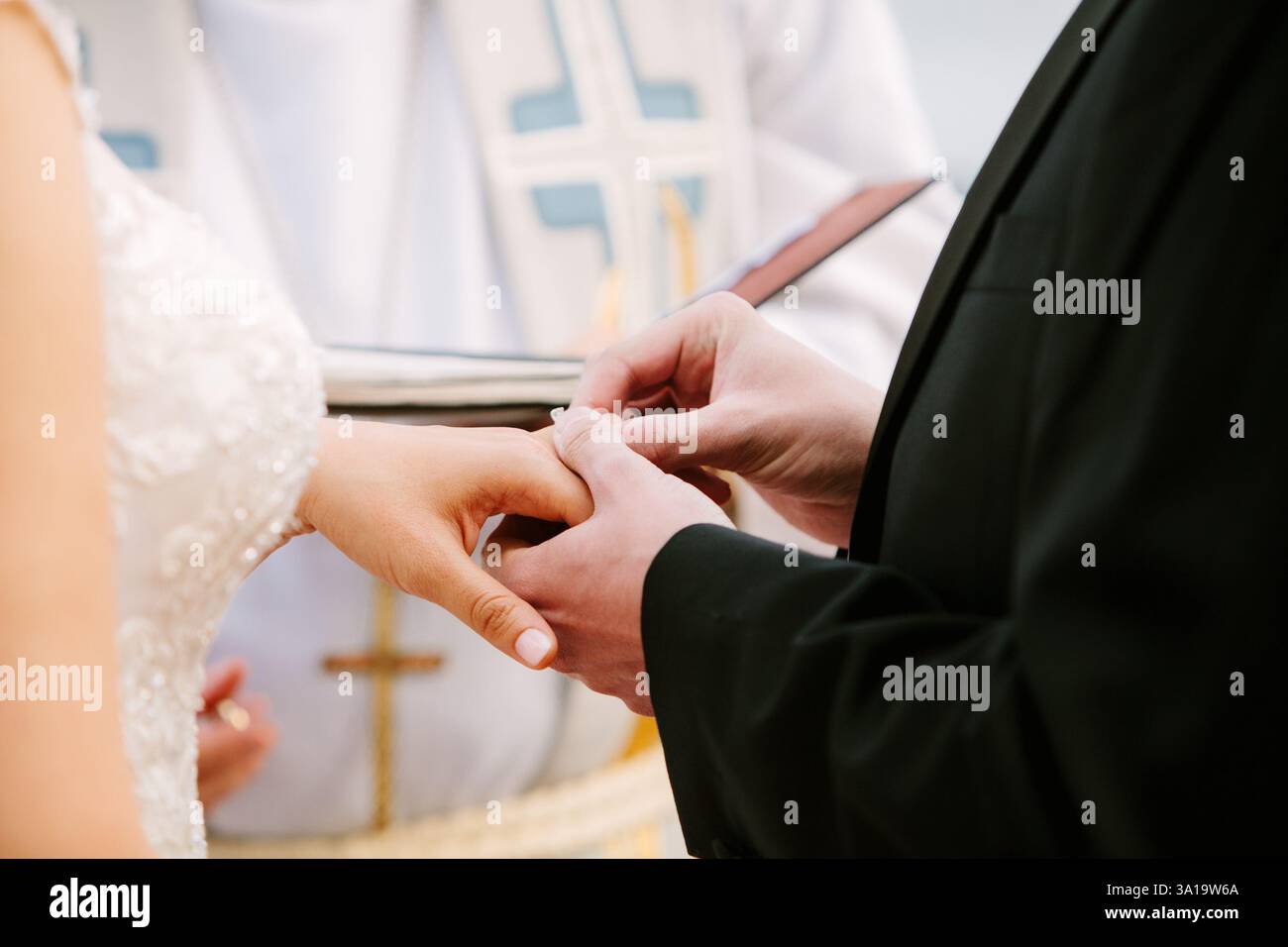 Due persone condividono un momento d'amore mentre scambiano le fedi nuziali su una splendida spiaggia al tramonto. Foto Stock