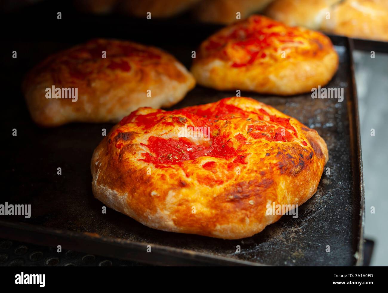 Mini pizza con salsa di pomodoro cotto in forno a legna in panetteria. Foto Stock