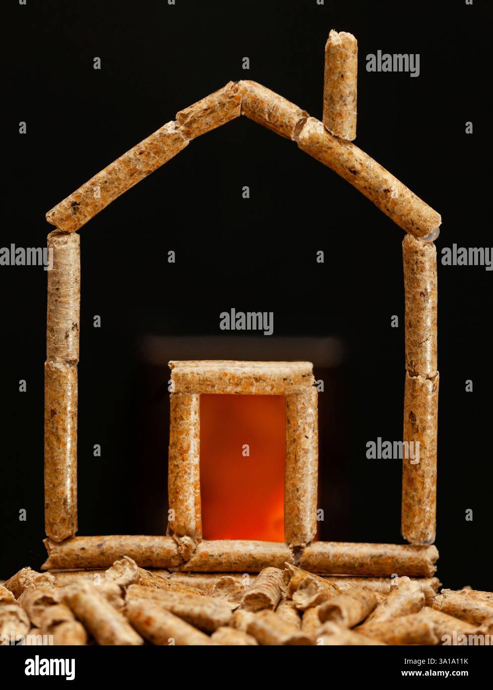 Casa in miniatura fatta con pellet di legno. Concetto di riscaldamento con camera di combustione in background. Foto Stock