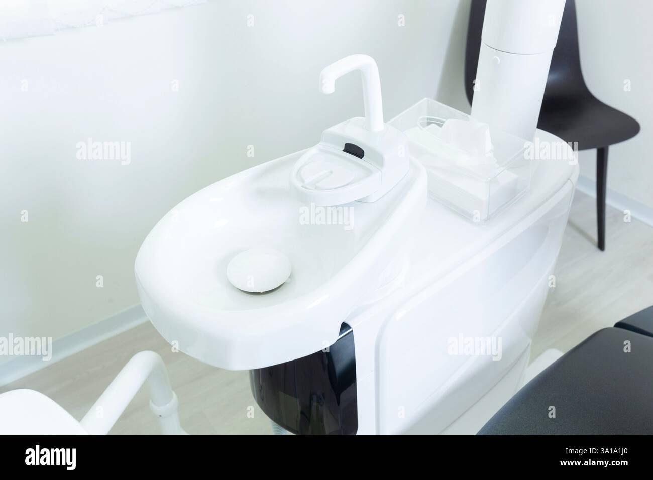 Lavabo bianco con rubinetto e tessuti in una clinica dentale moderna, per garantire il comfort e l'igiene del paziente durante le procedure odontoiatriche Foto Stock