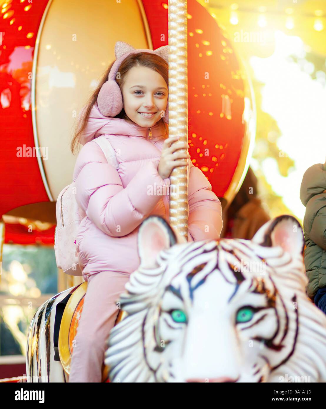 Un bambino felice si diverte con un giro in giostra su una tigre bianca in una fiera di natale o in un parco divertimenti Foto Stock