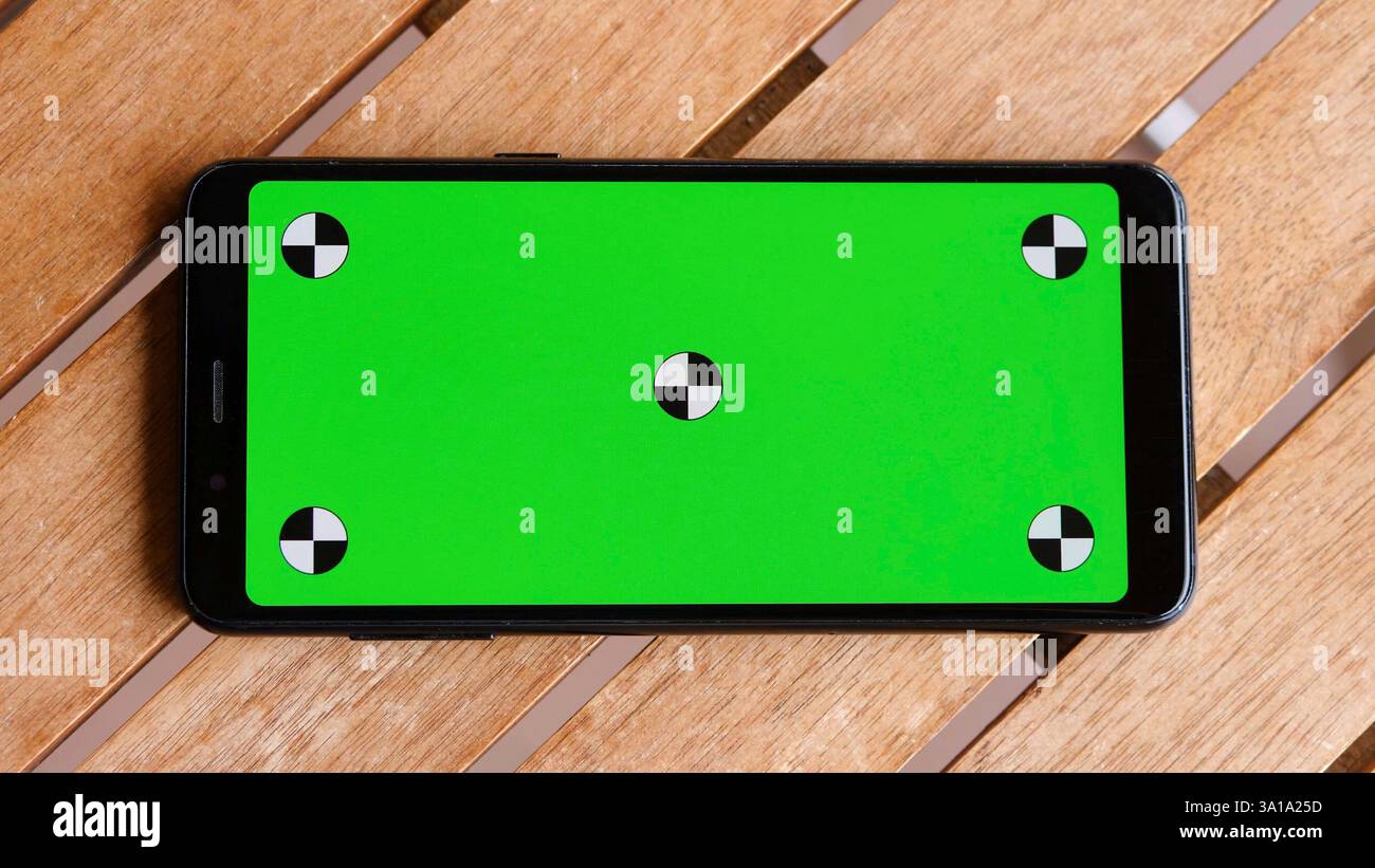 Vista dall'alto dello smartphone posizionare il telefono sul tavolo in legno con schermo verde, chiudere il telefono cellulare sul desktop marrone con chiave cromatica e marcatori. Foto Stock