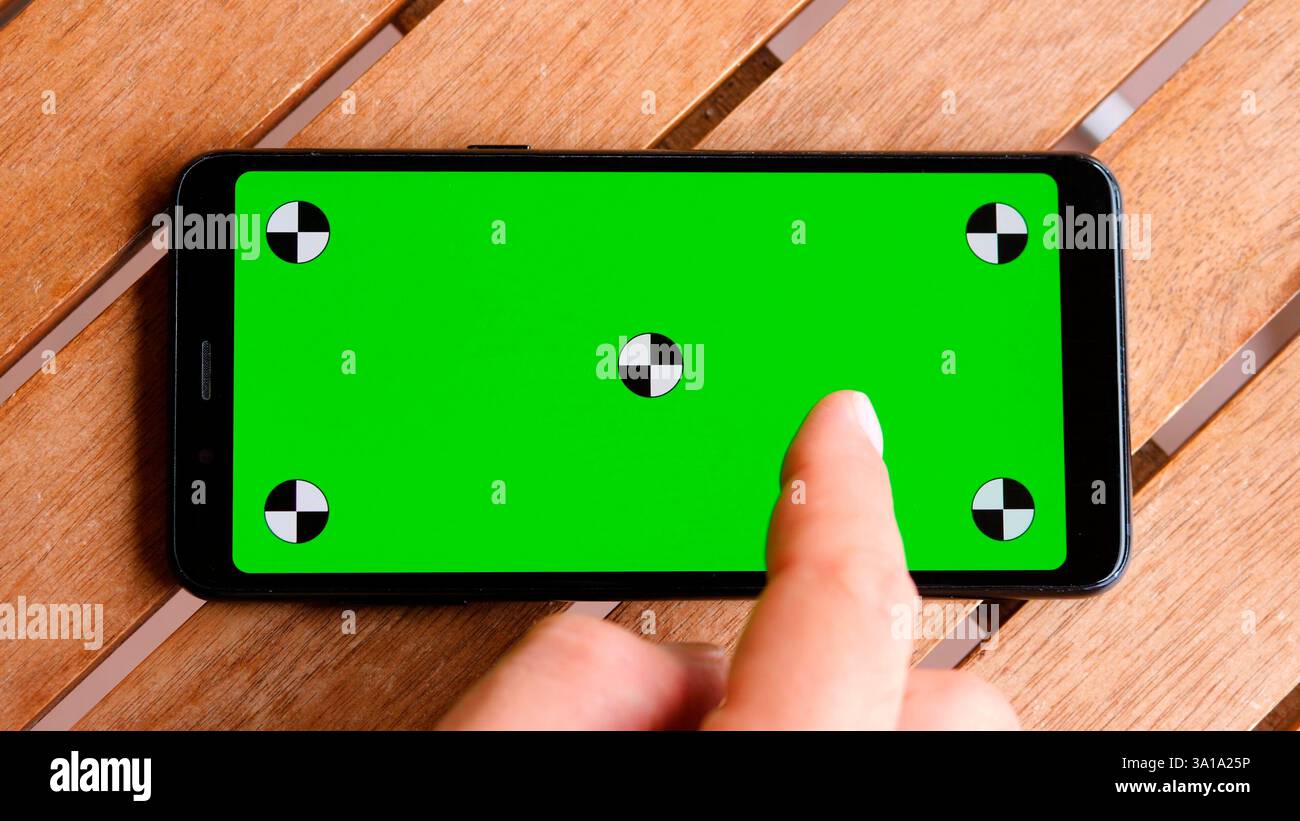 Vista dall'alto dello smartphone posizionare il telefono sul tavolo in legno con schermo verde, chiudere il telefono cellulare sul desktop marrone con chiave cromatica e marcatori. Foto Stock