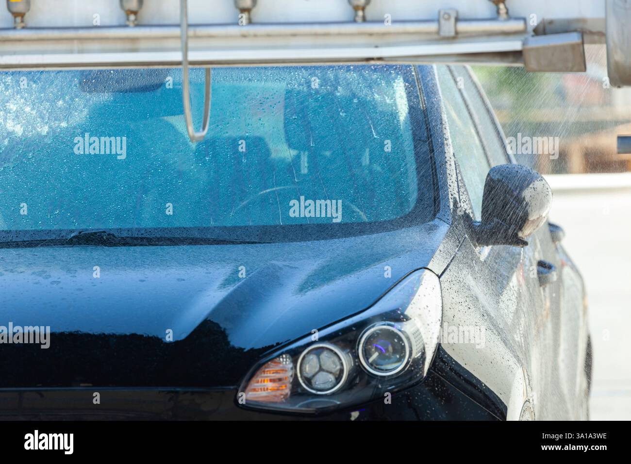 L'auto nera viene pulita da un sistema di autolavaggio automatico Foto Stock
