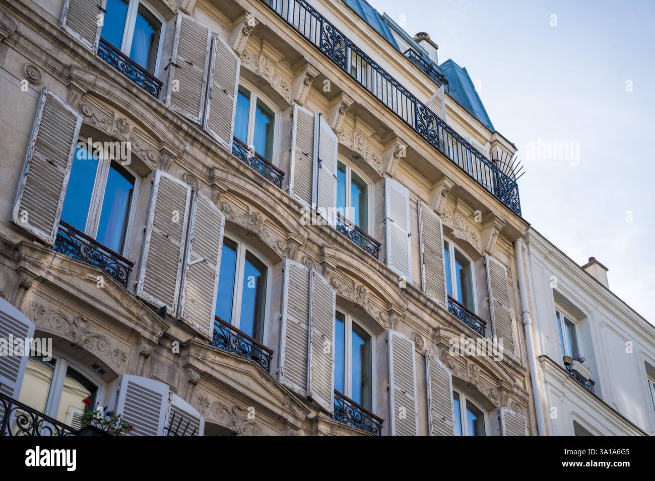 Eleganza architettonica di un classico edificio parigino caratterizzato da facciate dettagliate e affascinanti balconi in un ambiente urbano sereno Foto Stock