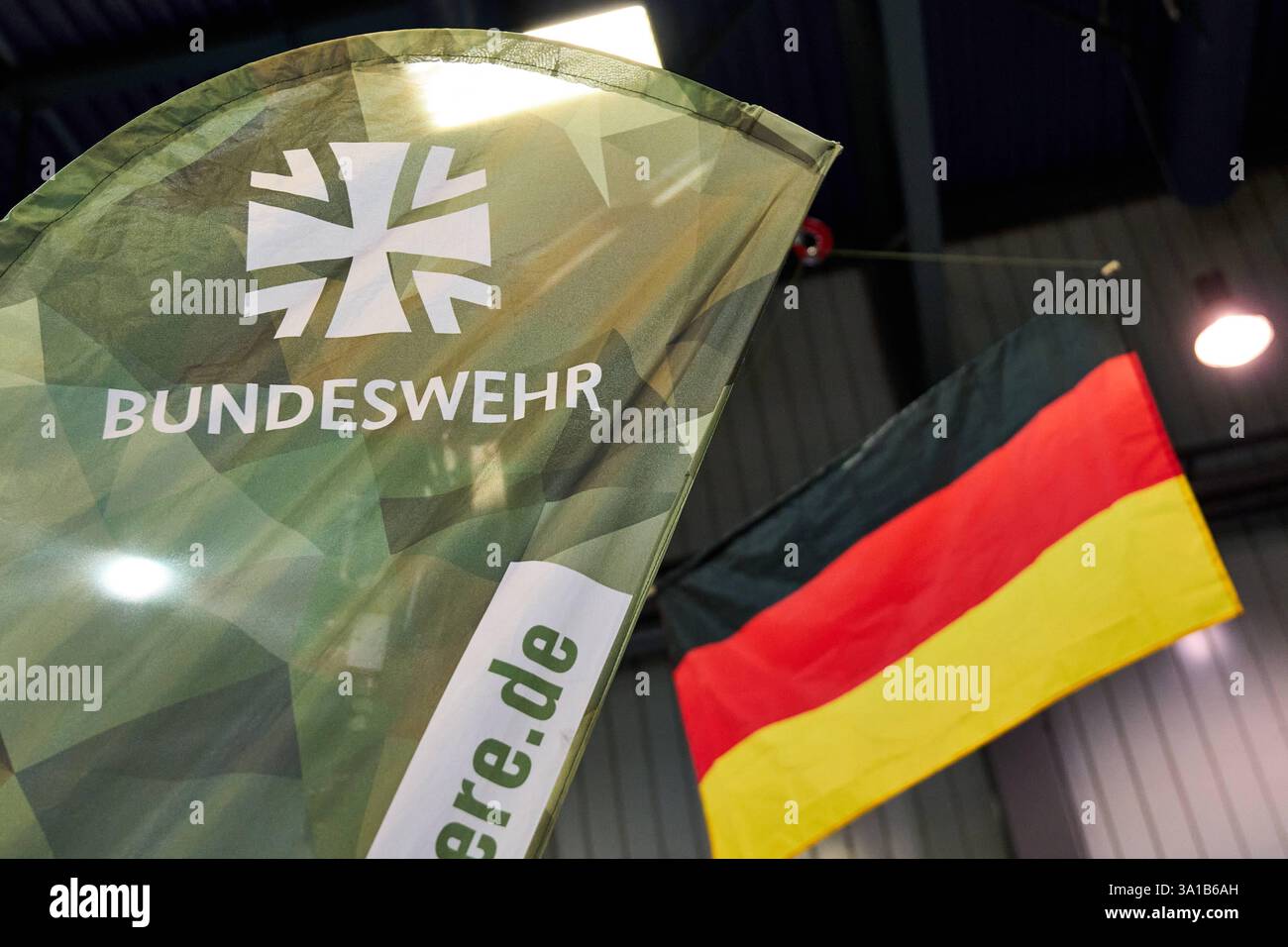 Augusta, Baviera, Germania - 7 marzo 2025: Stand della Bundeswehr alla fiera AFAIR di Augusta. Una bandiera della Bundeswehr con motivo mimetico e la bandiera tedesca *** Bundeswehr-Messestand auf der AFAIR Messe ad Augusta. Eine Bundeswehr-Fahne mit Tarnmuster und die deutsche Flagge Foto Stock