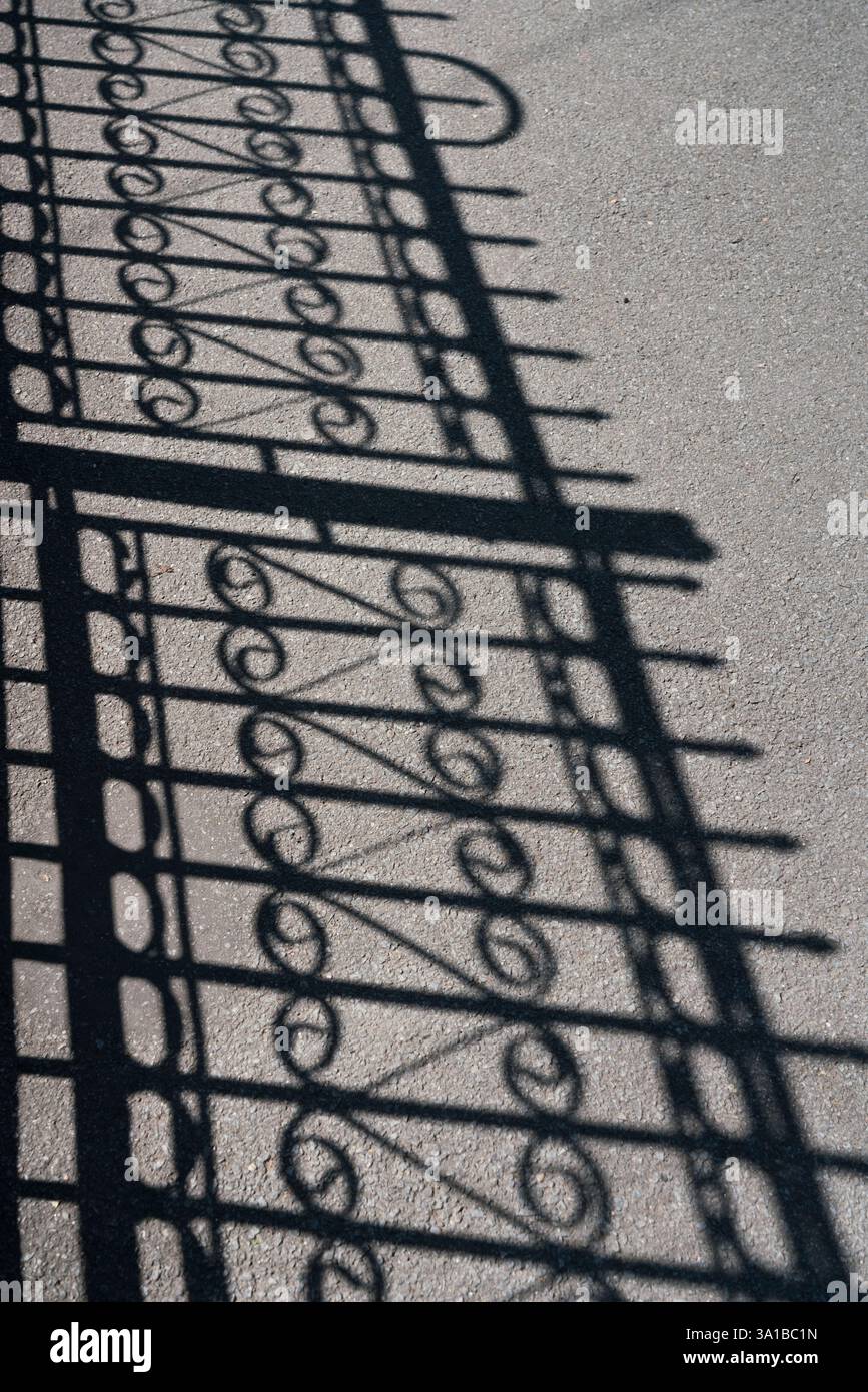 Ombra del punto di iniezione in metallo ornato sull'asfalto Foto Stock