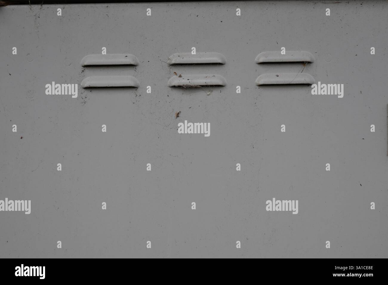 Un muro bianco con tre buchi. I fori sono in fila e sono distanziati Foto Stock