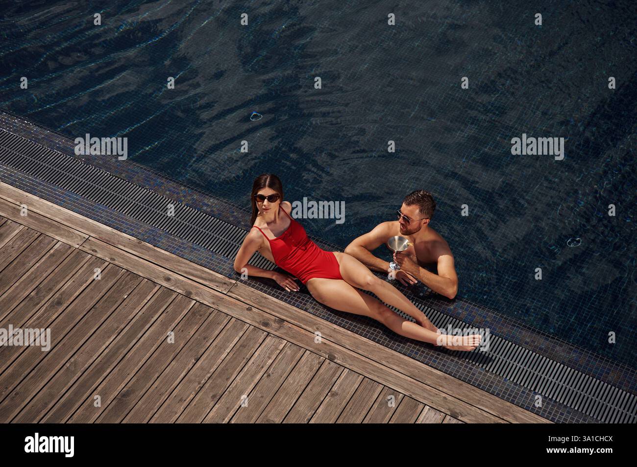 Con un cocktail. L'uomo con donna è in piscina insieme. Foto Stock