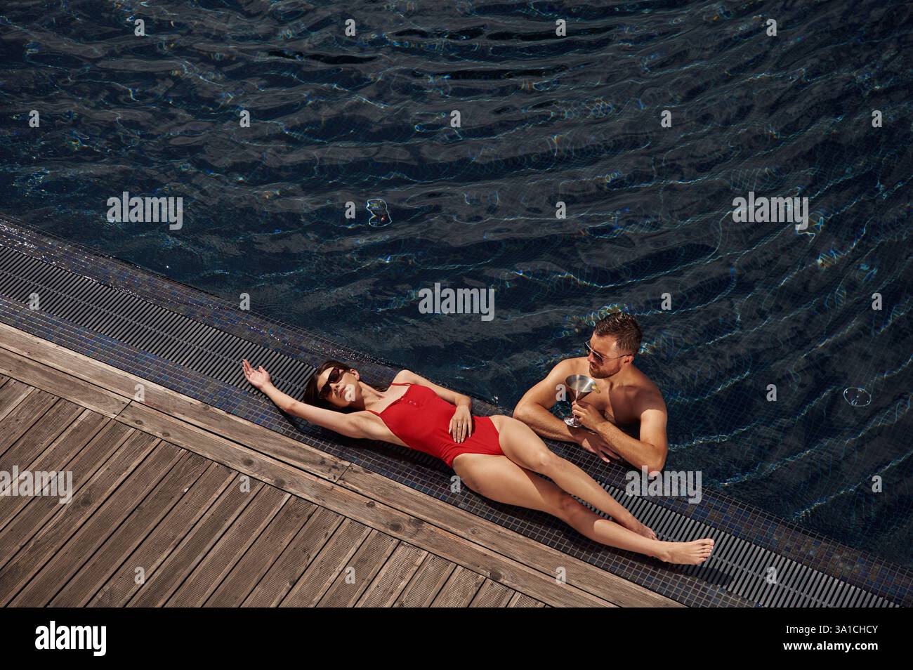 Con un cocktail. L'uomo con donna è in piscina insieme. Foto Stock