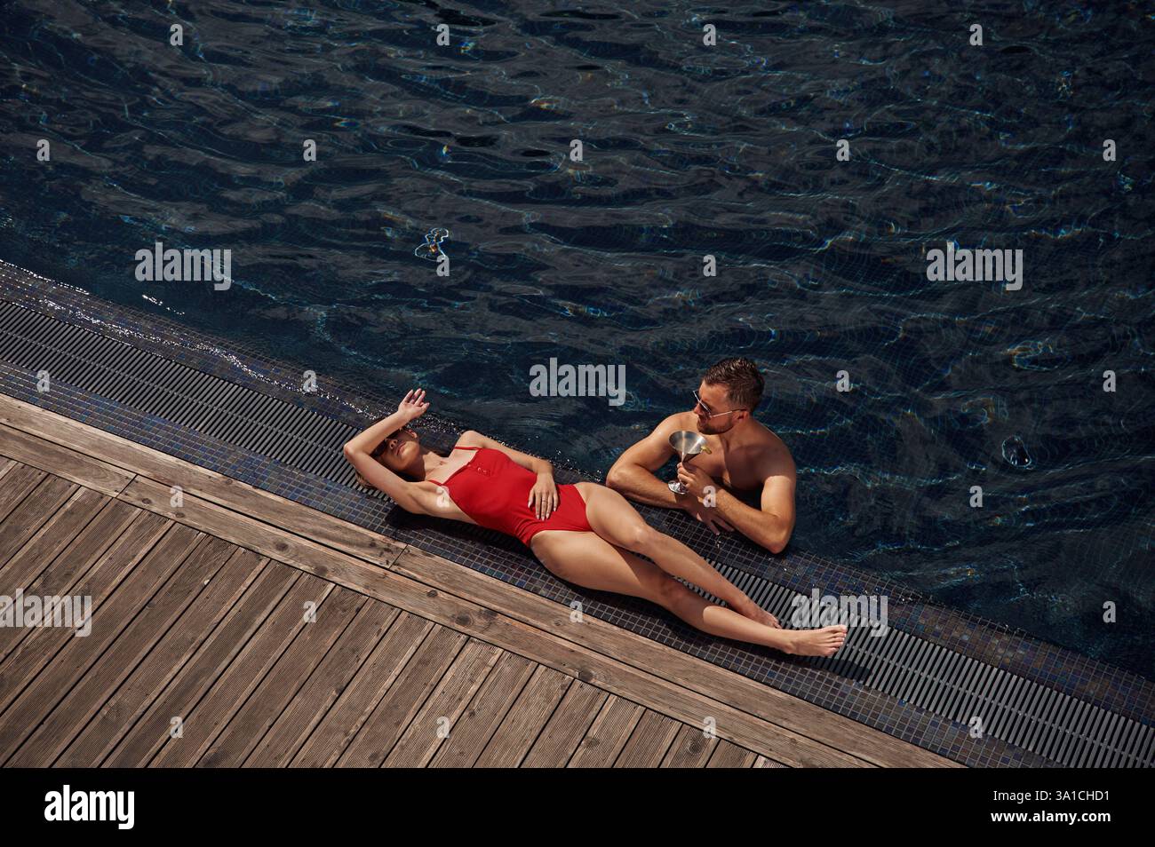 Con un cocktail. L'uomo con donna è in piscina insieme. Foto Stock