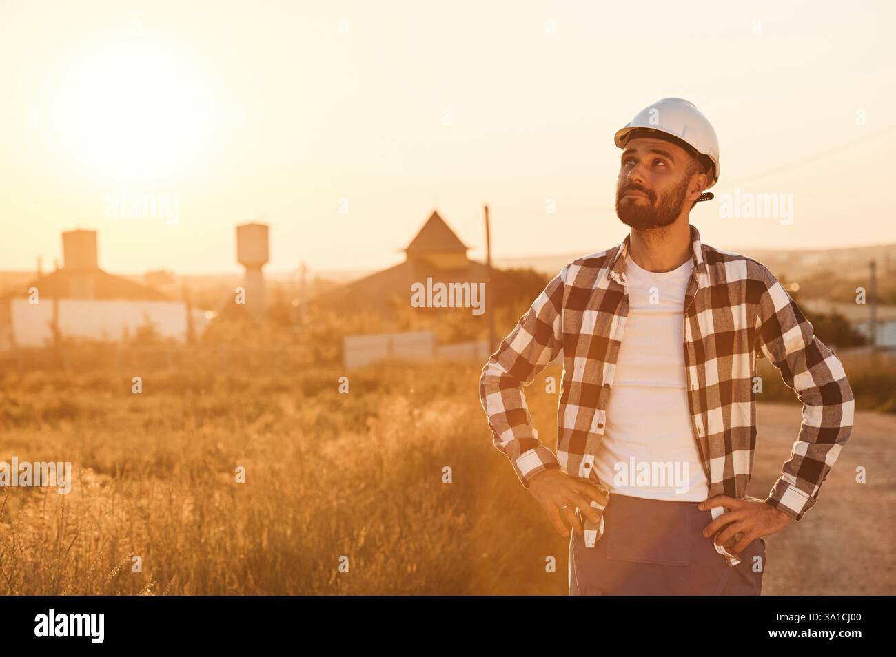 L'uomo con elmetto e' all'aperto contro la luce del tramonto. Scena rurale. Foto Stock