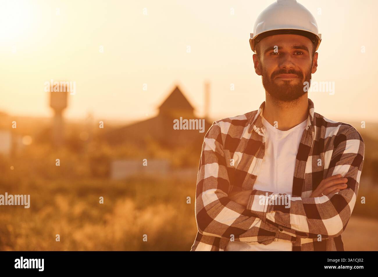 L'uomo con elmetto e' all'aperto contro la luce del tramonto. Scena rurale. Foto Stock