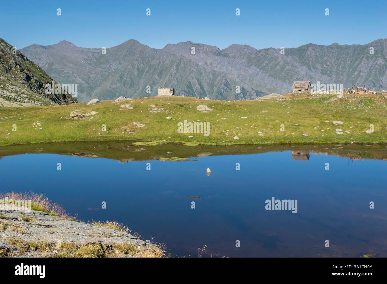 Uno splendido lago alpino che riflette le montagne circostanti, catturando la bellezza della natura incontaminata. Una destinazione perfetta tranquilla e remota. Foto Stock