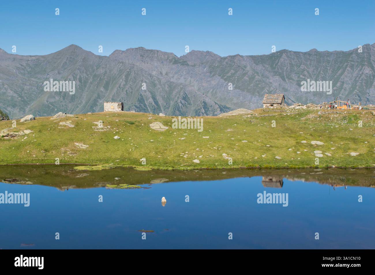 Uno splendido lago alpino che riflette le montagne circostanti, catturando la bellezza della natura incontaminata. Una destinazione perfetta tranquilla e remota. Foto Stock