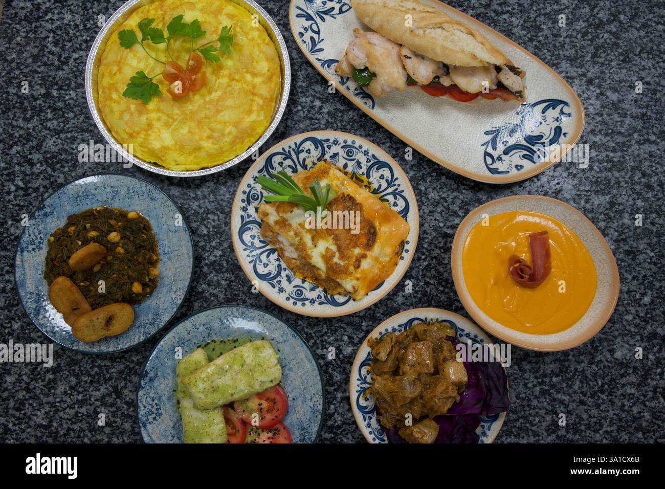 Un tavolo con una varietà di piatti, tra cui un panino, un'insalata e una ciotola di zuppa Foto Stock