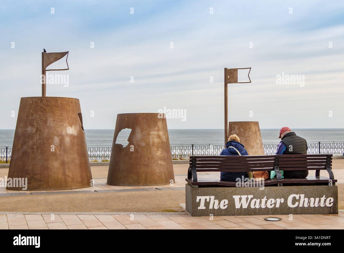 Coppia seduta accanto a castelli di sabbia in acciaio corten sculture installazione artistica artista Richard Broderick Promenade città spagnola whitley Bay tyne & Wear regno unito Foto Stock