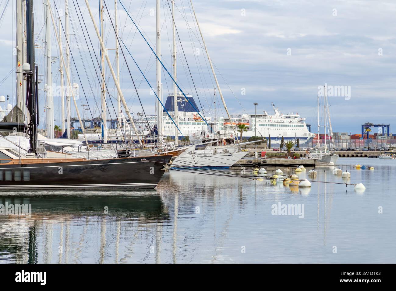 Valencia, Spagna - 23 febbraio 2025: Serena marina con diversi yacht e piccole imbarcazioni attraccate in acque calme. Un grande traghetto è visibile. Foto Stock