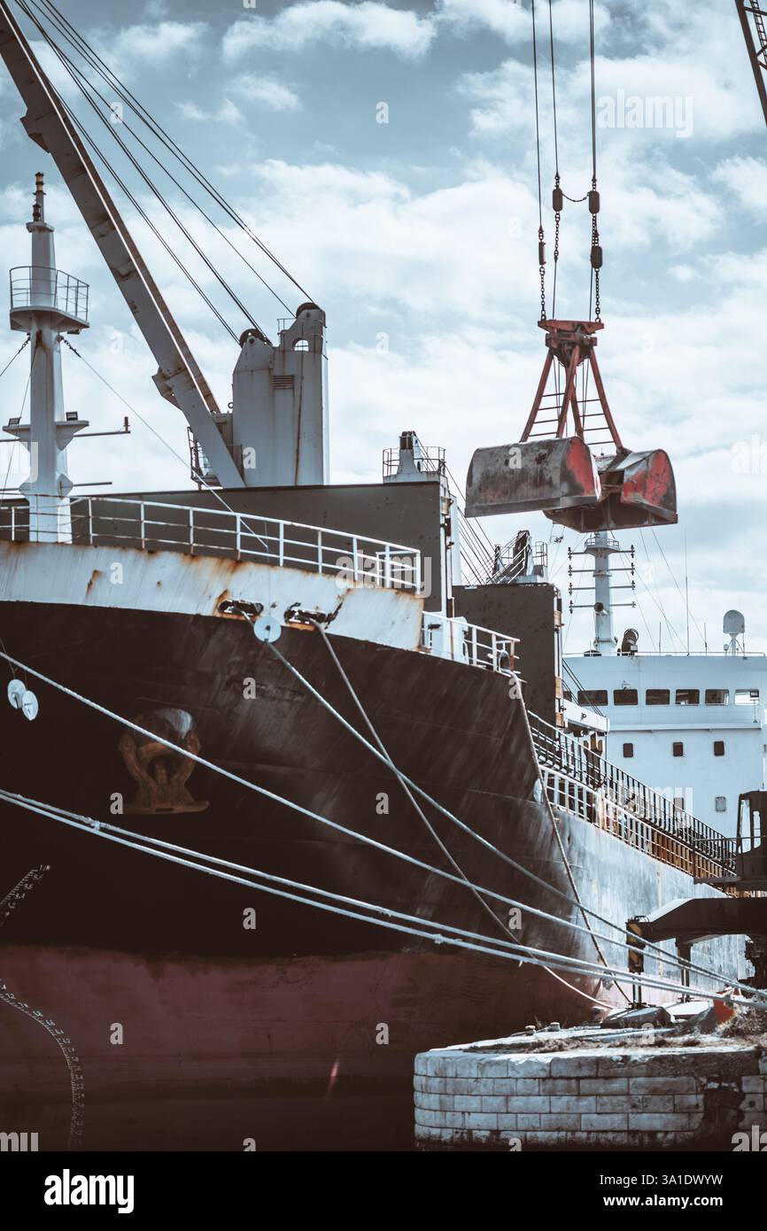 Portarinfuse ancorata in un porto durante le operazioni di carico. Una gru con benna mordente sta trasferendo materiale sfuso sulla nave. La nave e' rus' Foto Stock