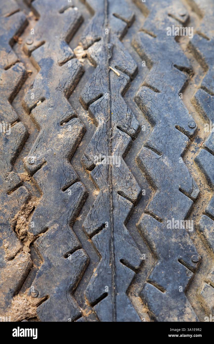 Primo piano di un vecchio pneumatico con fango incastrato tra le sporgenze usurate Foto Stock