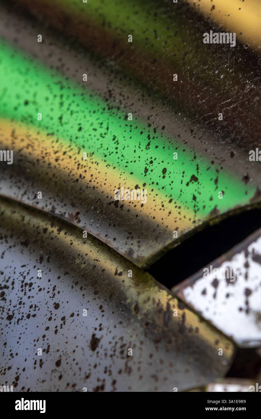 Specchio invecchiato con crepe e punti degradati in cui il supporto riflettente è scomparso, distorcendo le forme nelle tonalità verde e giallo Foto Stock