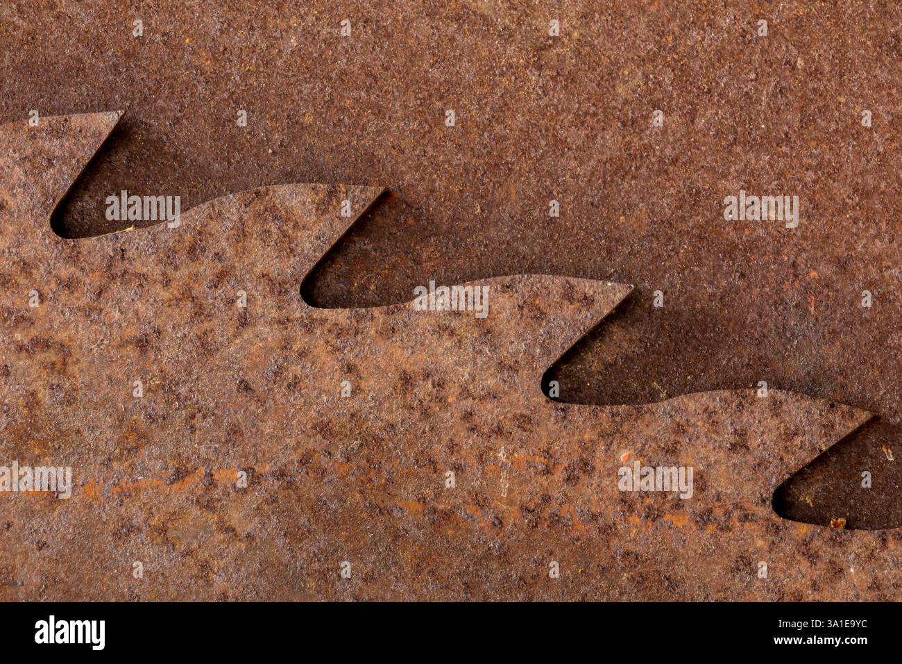 Primo piano dei denti arrugginiti della sega a nastro su uno sfondo metallico corroso. I bordi frastagliati e resistenti agli agenti atmosferici contrastano con la superficie ruvida ossidata Foto Stock