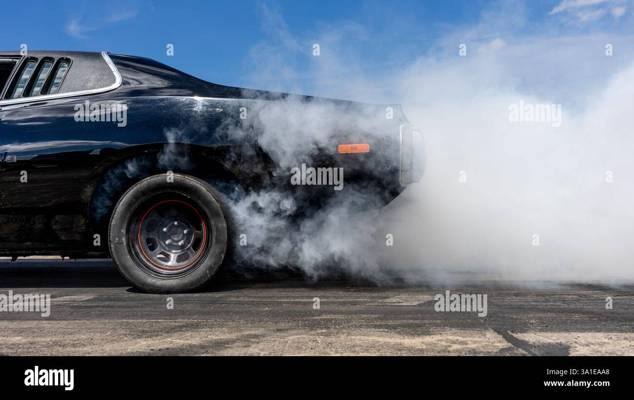Alla deriva, con il fumo proveniente da sotto le ruote di un'auto sportiva. Preparazione per l'inizio. Foto Stock